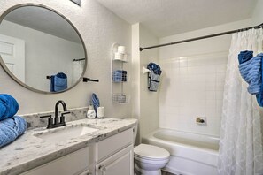 Une salle de bain équipée d’un lavabo, d’un miroir, de toilettes et d’une baignoire.