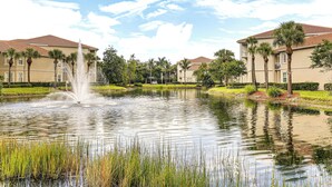 A residential area with a fountain in the foreground, surrounded by a pond with water lilies and reeds. - Work, Swim + Play in Ft Myers: Resort Condo Stay! (Fort Myers)