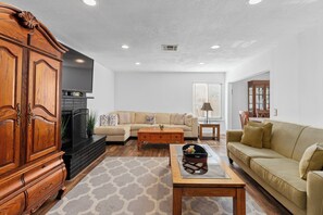A living room with a wooden cabinet, a beige sofa, a coffee table, and a fireplace.
