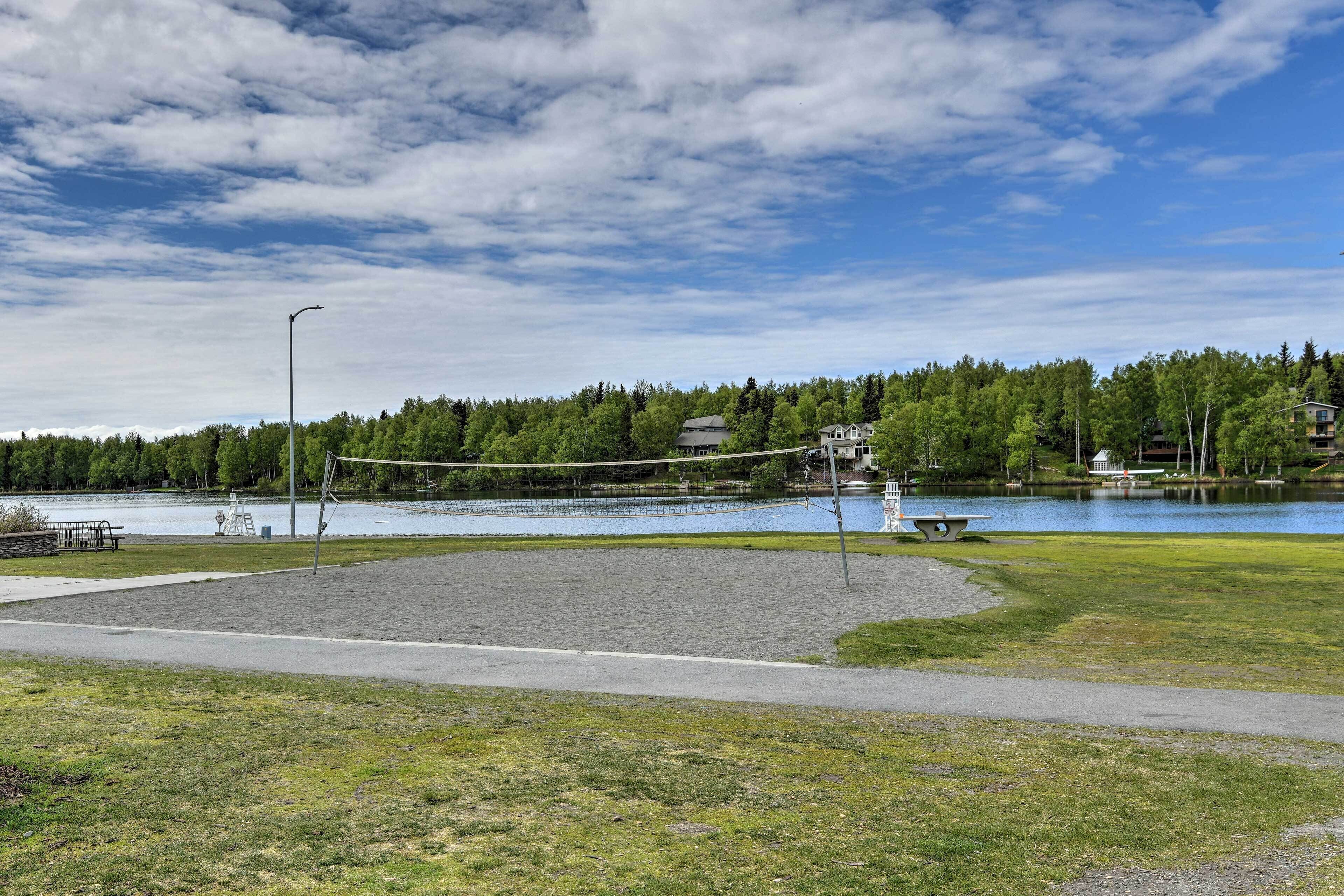 A park with a volleyball net, a bench, and a path.