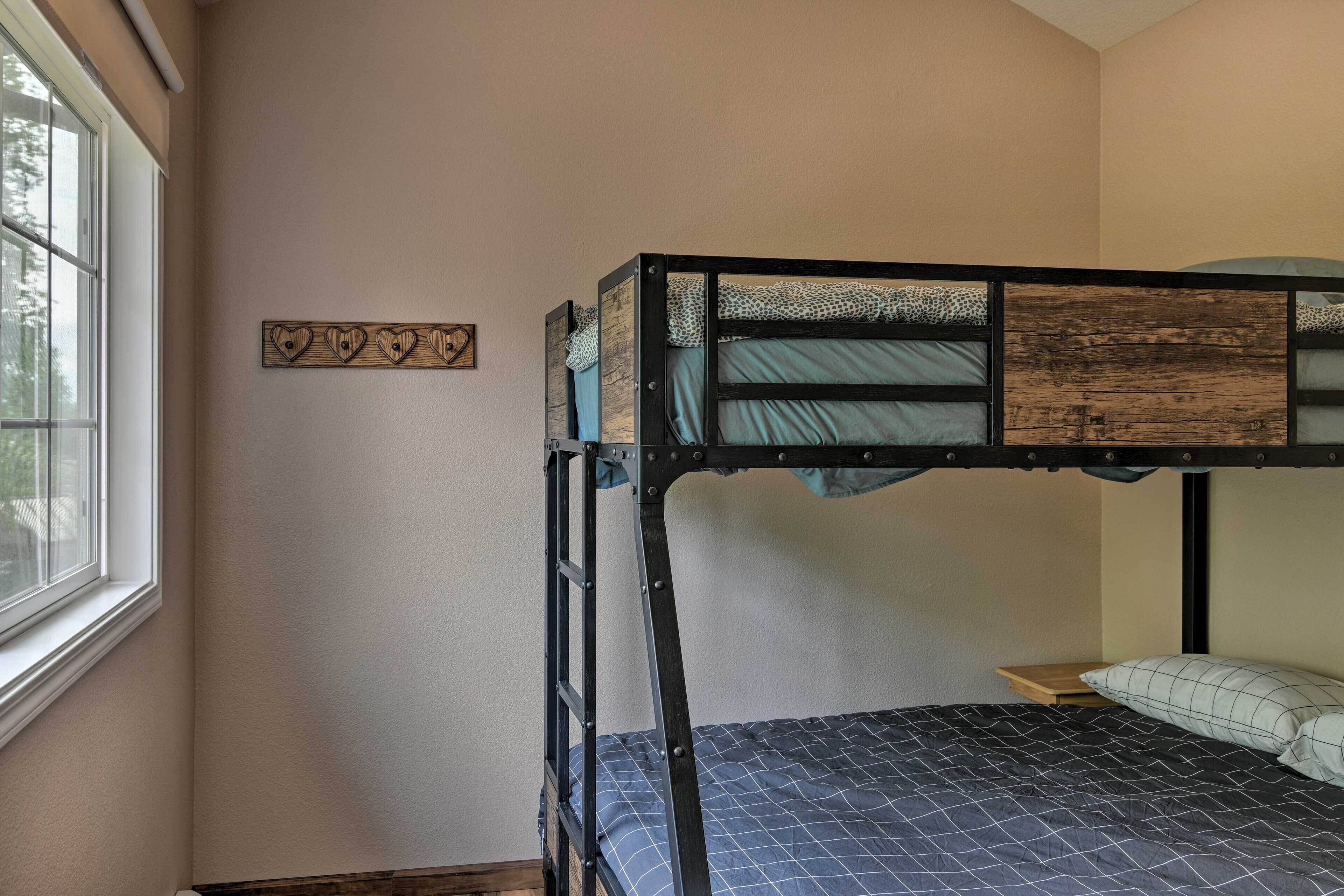 A bunk bed with a ladder, a window, and a wall decoration.