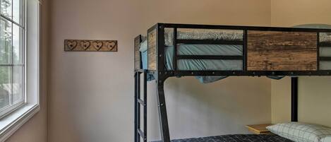 A bunk bed with a ladder, a window, and a wall decoration.
