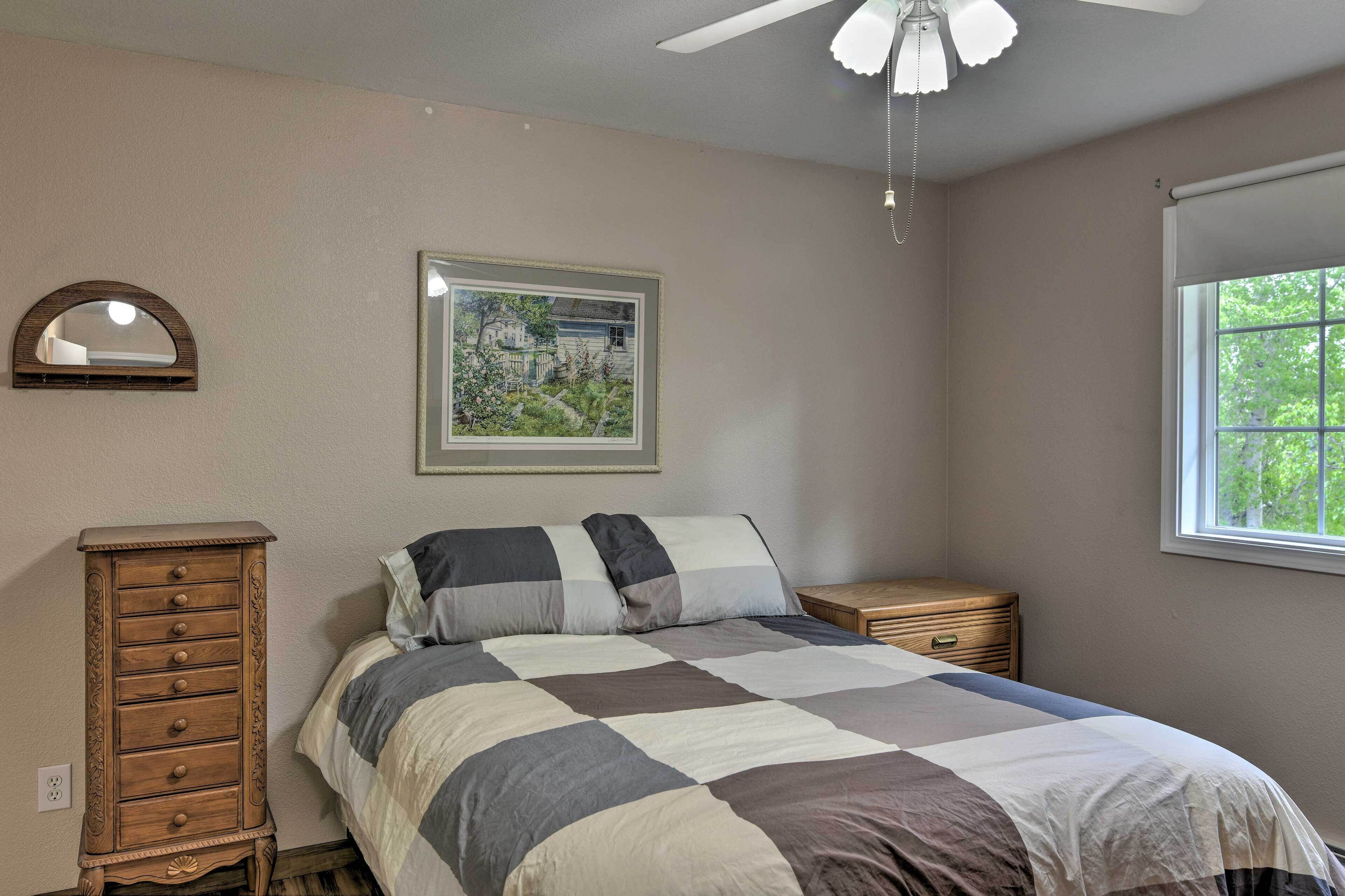 A bedroom with a bed, dresser, nightstand, framed picture, and window.