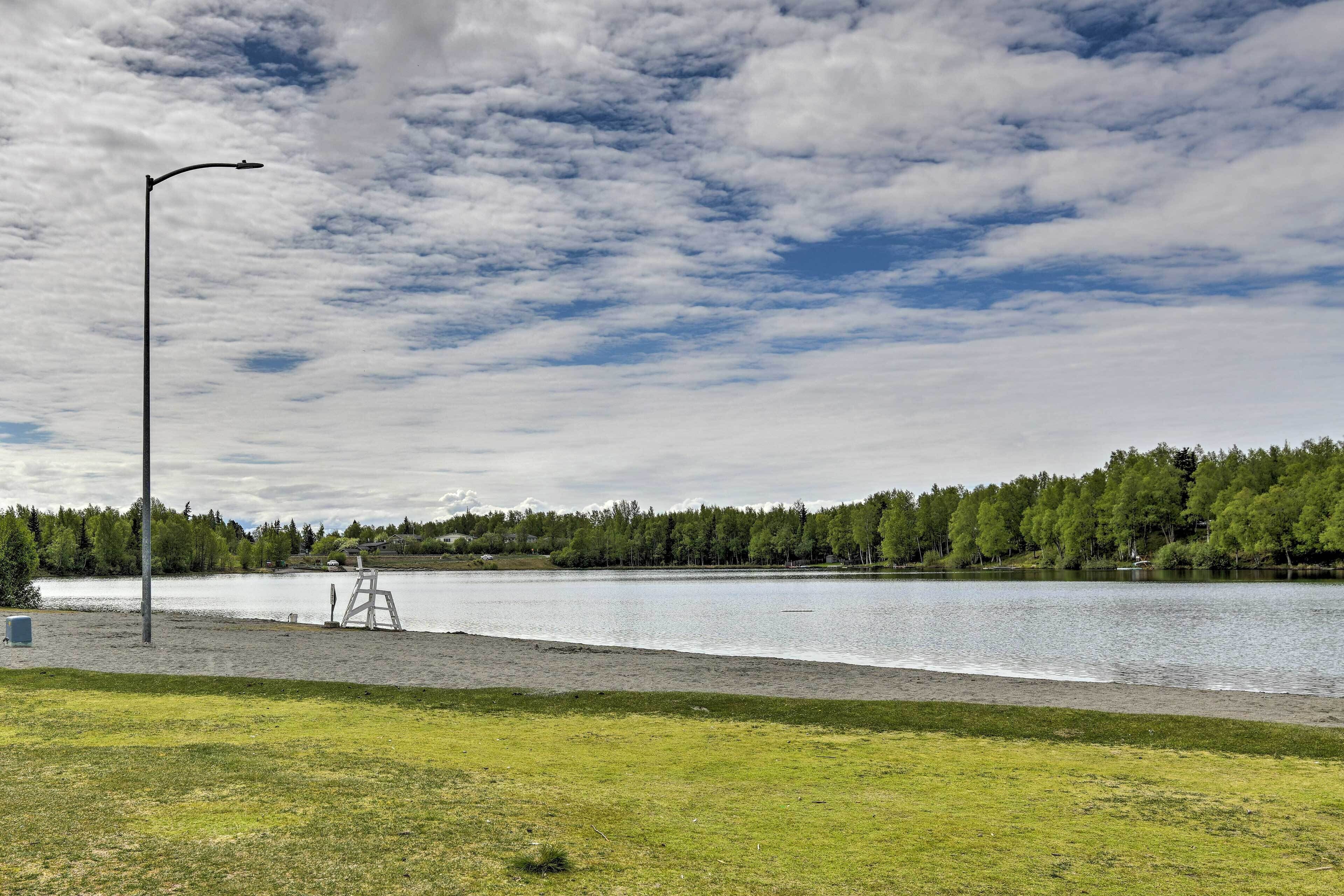 A lakeside view with a grassy area, a wooden ladder, and a street lamp.