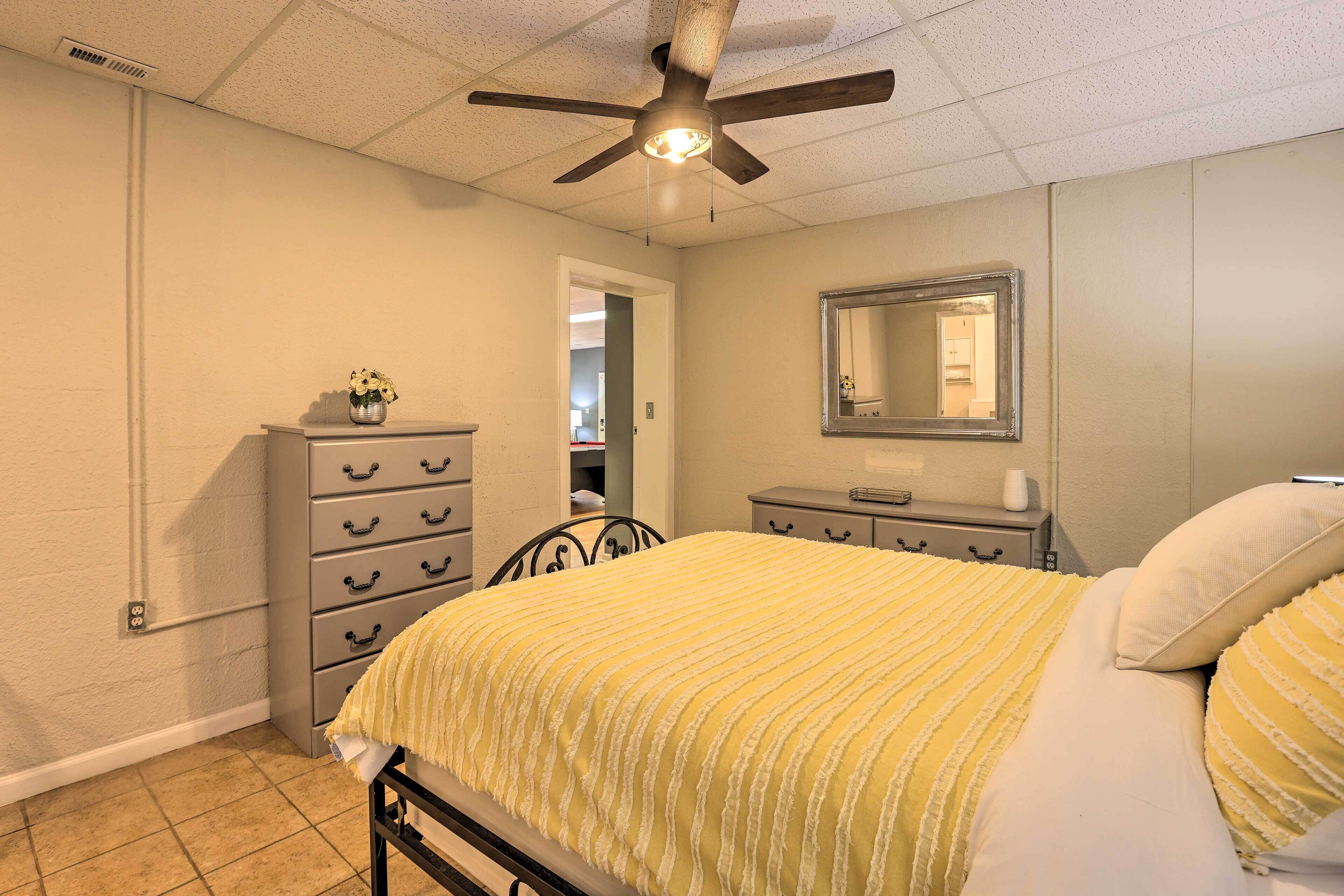 A bedroom with a bed, a dresser, a nightstand, a ceiling fan, and a mirror on the wall.