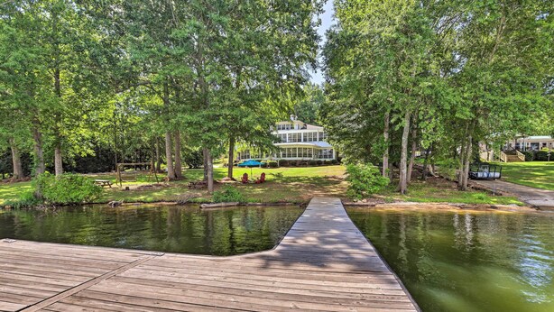 A wooden deck leading to a pond with a house in the background. - 'the B Haus' Lakefront Retreat w/ Boat Ramp! (Talladega)