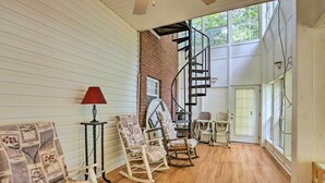 A room with wooden flooring, rocking chairs, a red lamp, and a spiral staircase leading to a loft area. - 'the B Haus' Lakefront Retreat w/ Boat Ramp! (Talladega)