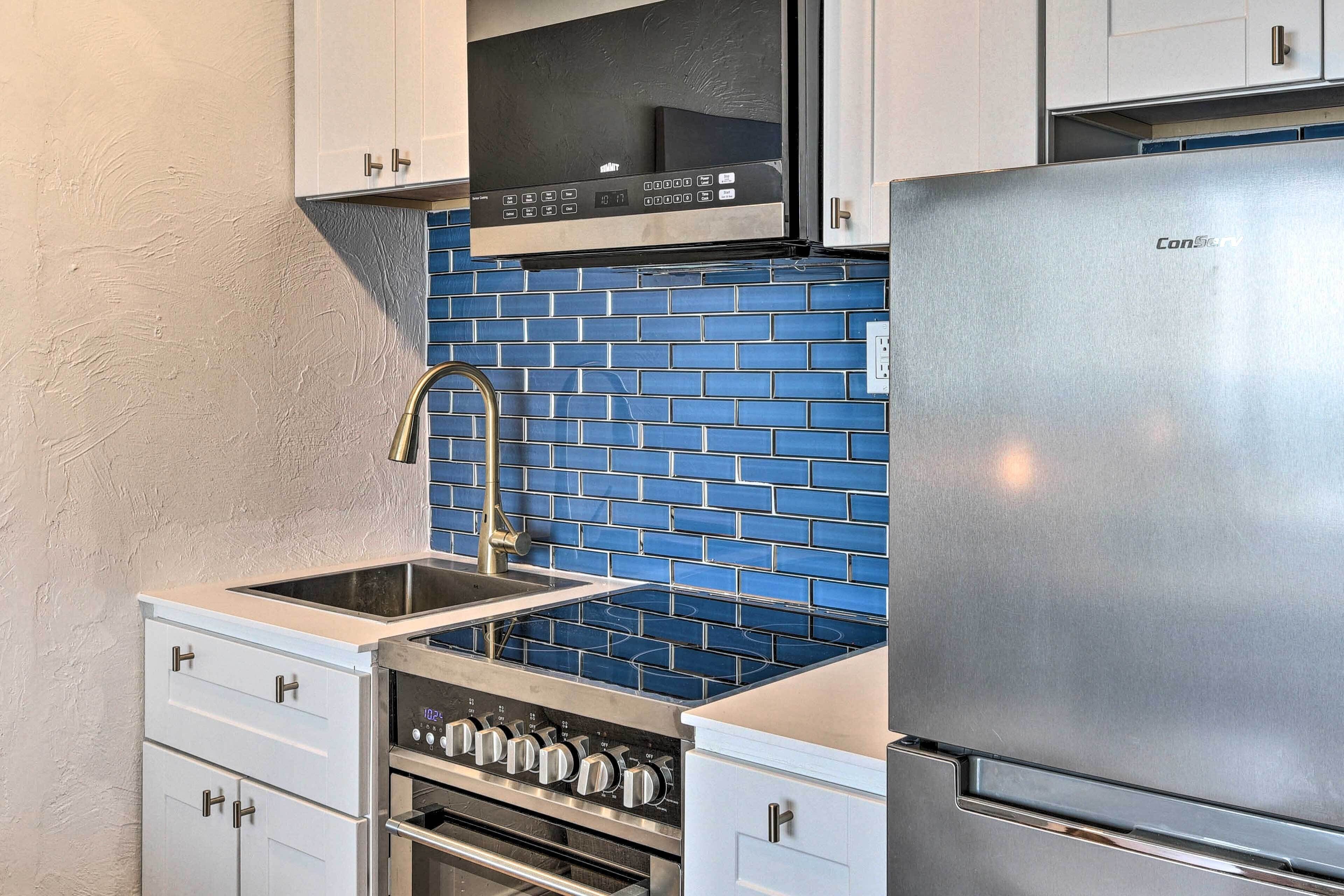 A kitchen with white cabinets, a stainless steel refrigerator, a microwave, and a stove.