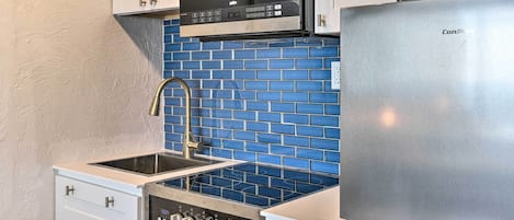 A kitchen with white cabinets, a stainless steel refrigerator, a microwave, and a stove.
