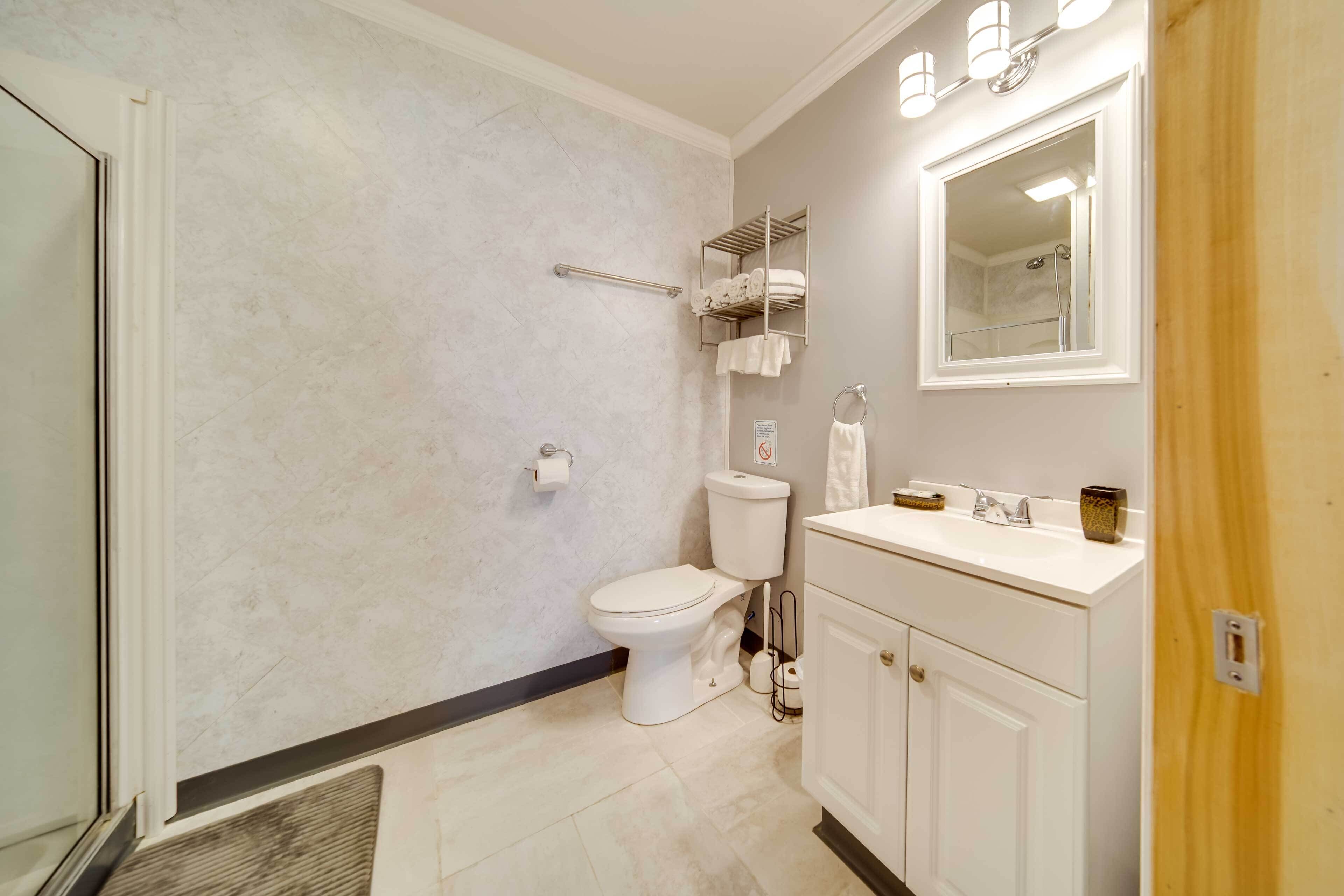 A bathroom with a toilet, sink, mirror, towel rack, and shower area.