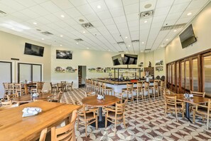 A spacious restaurant with multiple wooden tables and chairs, a central bar area, and a patterned floor.