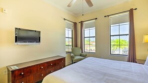 Een slaapkamer met een bed, een televisie aan de muur, een dressoir en een stoel.