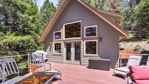 Een chalet met een terras, buitenmeubels en grote ramen.