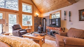 Een gezellige woonkamer met een stenen openhaard, een televisie en comfortabele zitplaatsen.