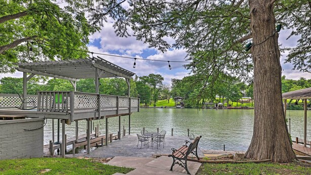 Une terrasse au bord du lac, agrémentée d’une pergola, de sièges d’extérieur et d’un grand arbre.