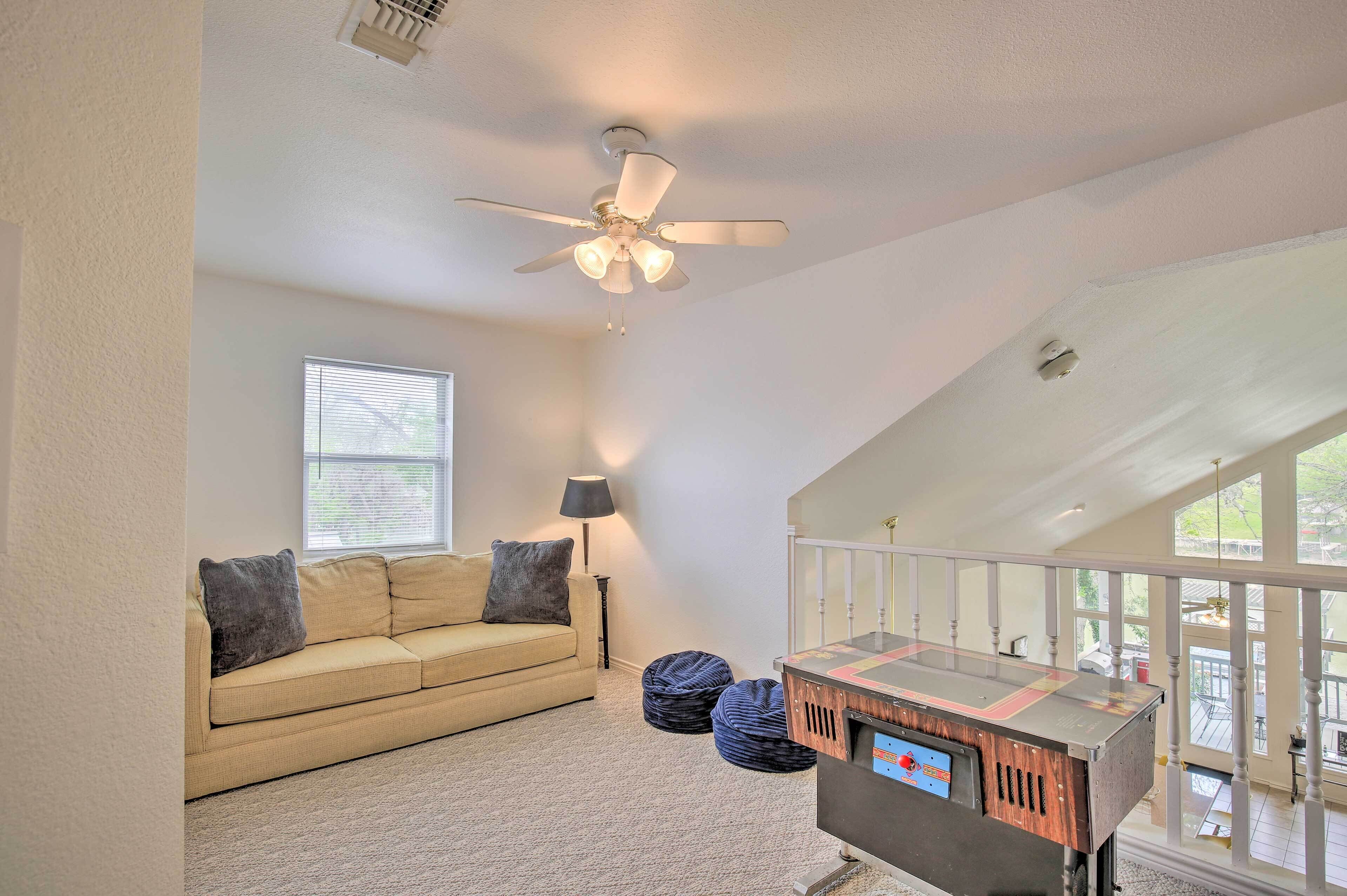 A living room with a ceiling fan, a sofa, bean bags, and a coffee table.