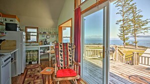 A cozy kitchen with a wooden chair by a large window overlooking a deck.