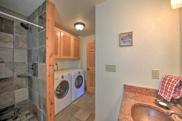 A laundry room with a washing machine and dryer, a wooden door, and a tiled shower area.