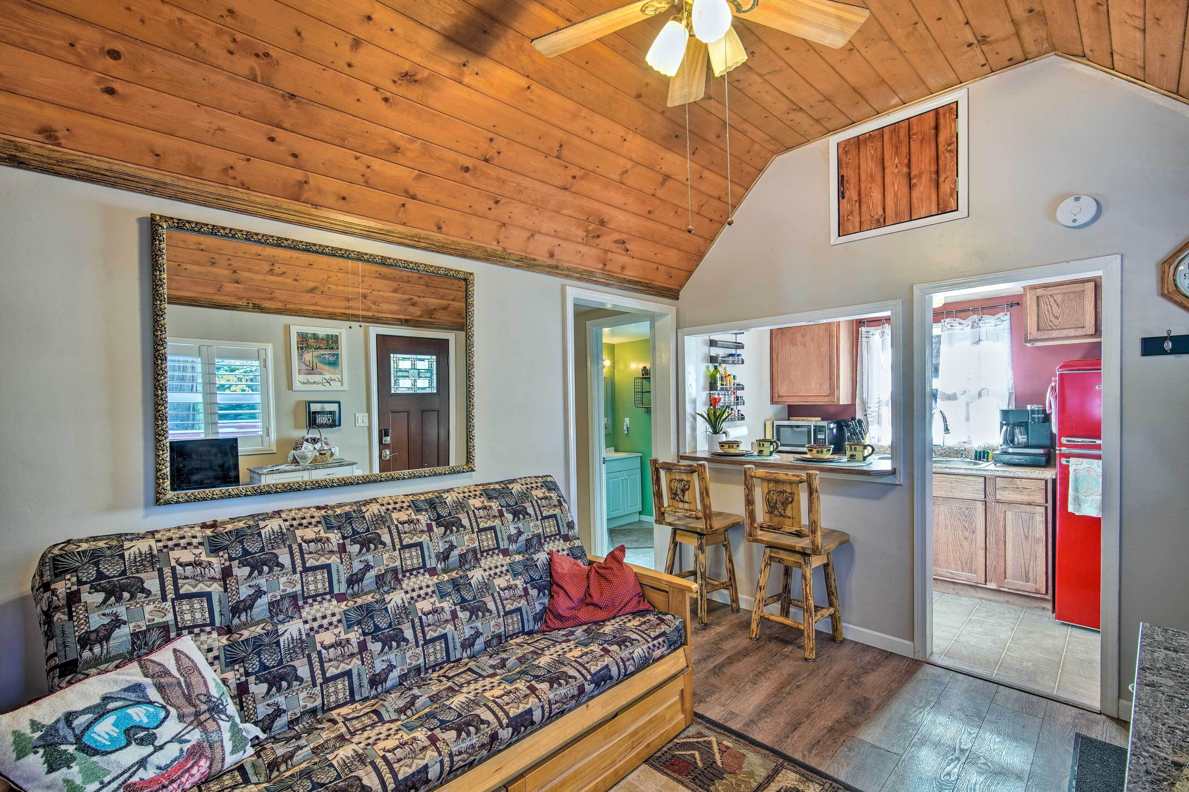 A cozy living room with a patterned sofa, a large mirror, and a wooden ceiling.