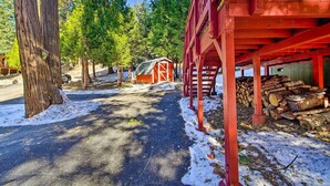 Un rustico chalet con facciata rossa, immerso in un paesaggio innevato tra alberi.