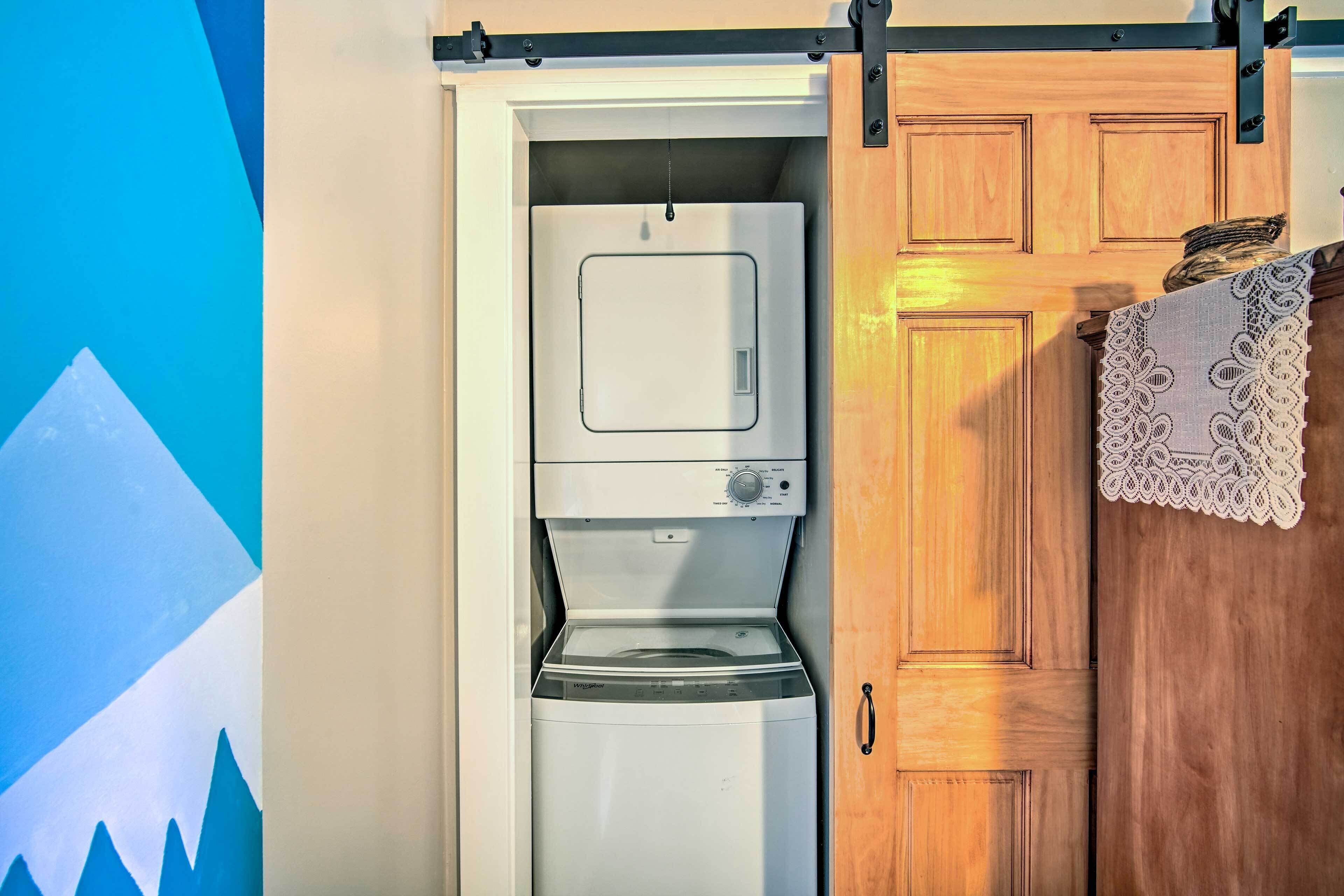A compact, white front-loading washing machine in a wooden cabinet with a lace doily.