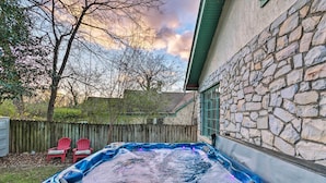 A hot tub in a backyard with a stone wall, two red Adirondack chairs, and a wooden fence. - 2 Mi to Hot Springs Nat'l Park: Hot Tub Haven! (Hot Springs)