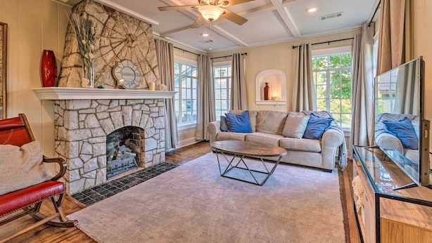 A living room with a stone fireplace, a ceiling fan, a sofa, and a coffee table. - 2 Mi to Hot Springs Nat'l Park: Hot Tub Haven! (Hot Springs)