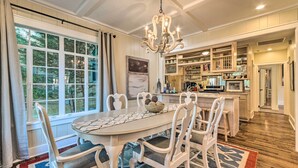 A dining area with a white table and chairs, a chandelier, and a view of the outdoors through large windows. - 2 Mi to Hot Springs Nat'l Park: Hot Tub Haven! (Hot Springs)