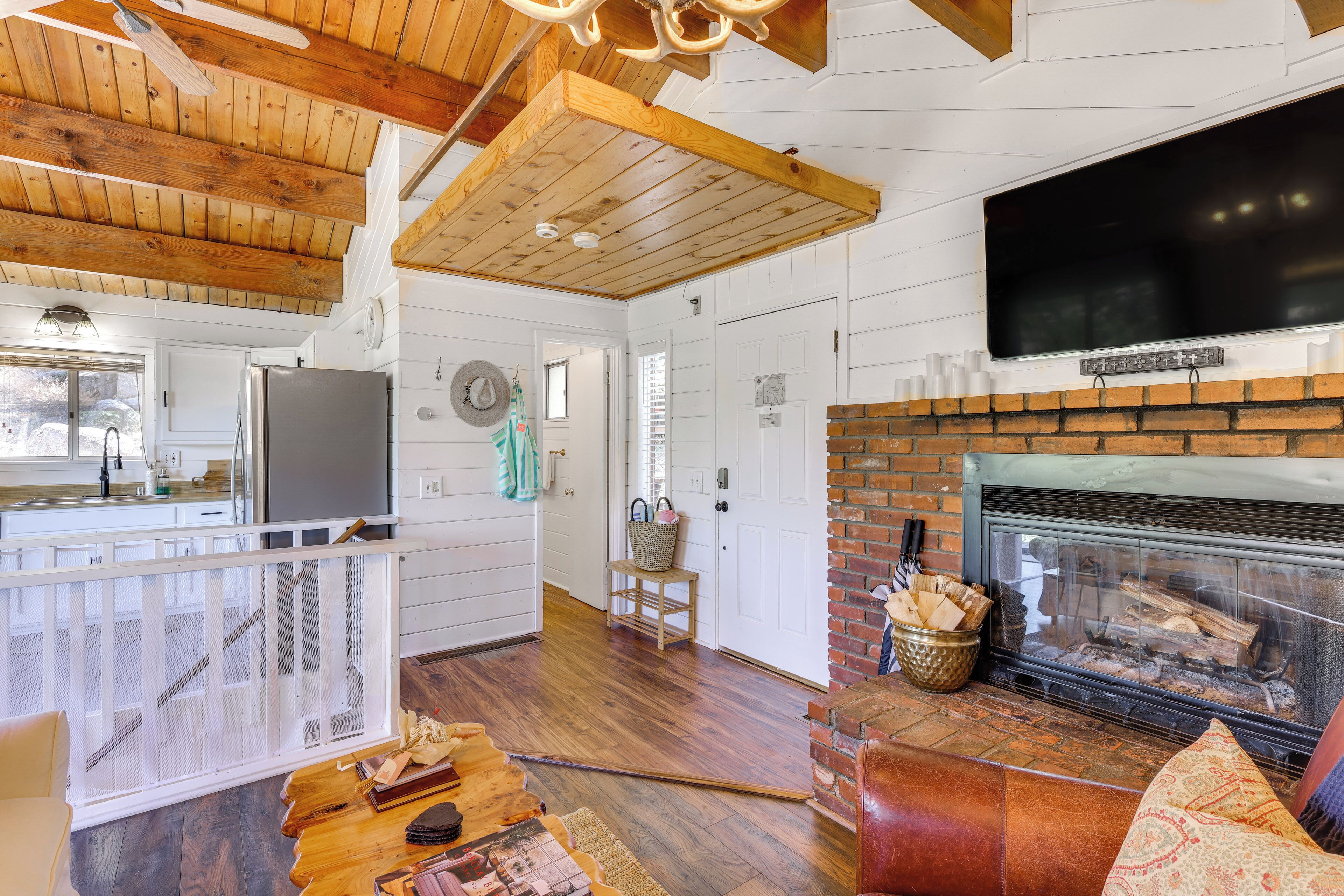 A spacious living area with a fireplace, wooden ceiling, and a television mounted above it.