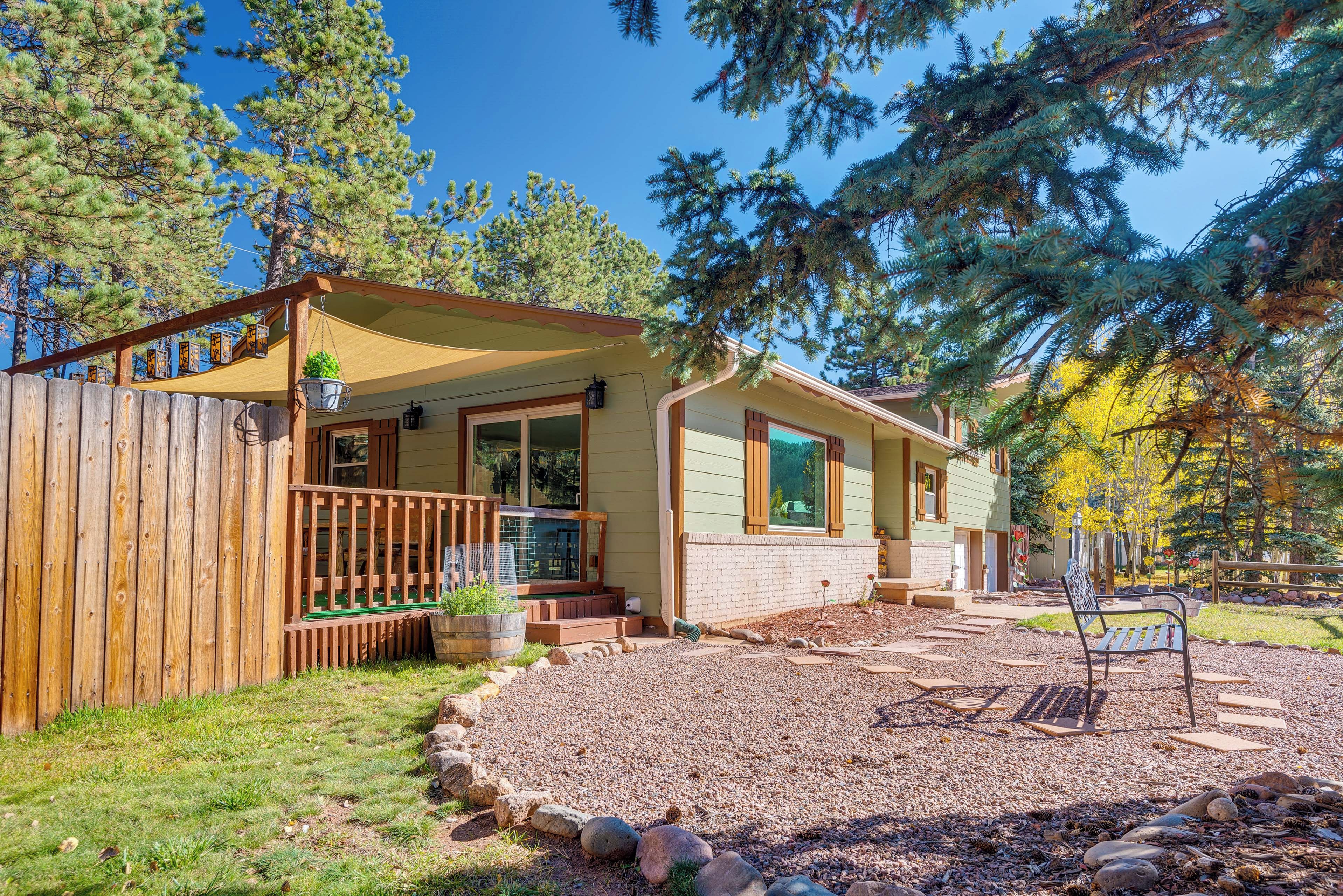 Une cabane dot ée d’un porche couvert, d’un espace patio avec un foyer et d’une clôture en bois.
