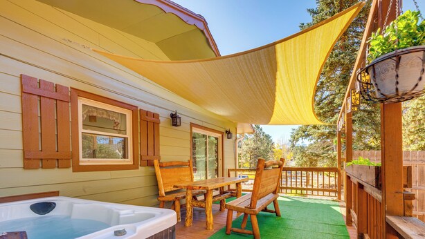 Une terrasse en bois avec un jacuzzi, des meubles en bois et un tapis vert.