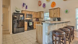 A kitchen with wooden cabinets, a refrigerator, a microwave, and a stone island with bar stools. - Pet-friendly Home w/ Deck: 1 Mi to Canyon Lake Fun (Canyon Lake)