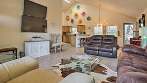 A spacious living room with a large flat-screen TV, leather sofas, a glass coffee table, and a kitchen area in the background. - Pet-friendly Home w/ Deck: 1 Mi to Canyon Lake Fun (Canyon Lake)