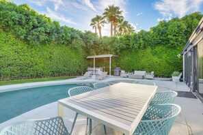 A poolside area with a wooden table and chairs, a barbecue grill, and a covered seating area. - 1 Mi to Dtwn Palm Springs: Home w/ Fire Pit! (Palm Springs)