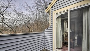 Een hoek van een huis met een houten terras en een schuifdeur die leidt naar een binnenruimte.