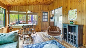 A wooden interior with a dining table, chairs, a sofa, a fireplace, and a map on the wall. - Peaceful Wooded Retreat at Lake Wallenpaupack! (Lake Ariel)
