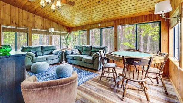 A wooden interior with two sofas, a dining table, and chairs. - Peaceful Wooded Retreat at Lake Wallenpaupack! (Lake Ariel)