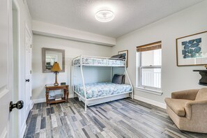 A bedroom with a bunk bed, a small table with a lamp, a chair, and a framed picture on the wall. - High-rise PCB Condo w/ Oceanfront Views & Pool! (Panama City Beach)