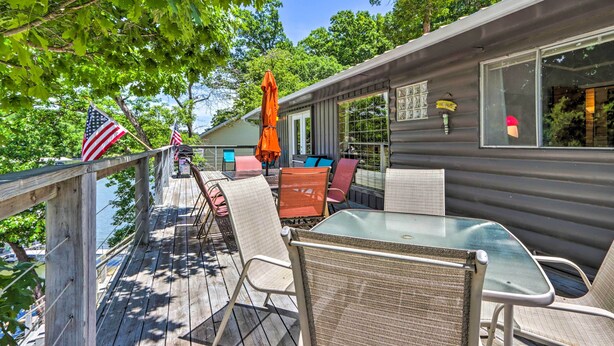 A deck with outdoor seating, a view of the water, and American flags. - Waterfront Home w/ 3 Decks on Lake of the Ozarks! (Sunrise Beach)