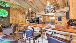 A wooden interior with a bar area, seating, and kitchen appliances. - Waterfront Home w/ 3 Decks on Lake of the Ozarks! (Sunrise Beach)