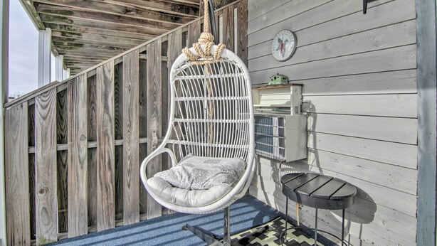 A hanging chair with a cushion, a small table, and a wall clock. - Central Studio w/ Deck: Walk to Shops & Dining! (Ocean City)