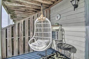 A hanging chair with a cushion, a small table, and a wall clock. - Central Studio w/ Deck: Walk to Shops & Dining! (Ocean City)