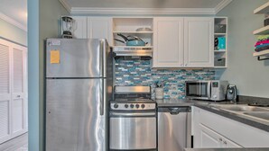 A modern kitchen with stainless steel appliances, a tiled backsplash, and white cabinetry. - Central Studio w/ Deck: Walk to Shops & Dining! (Ocean City)