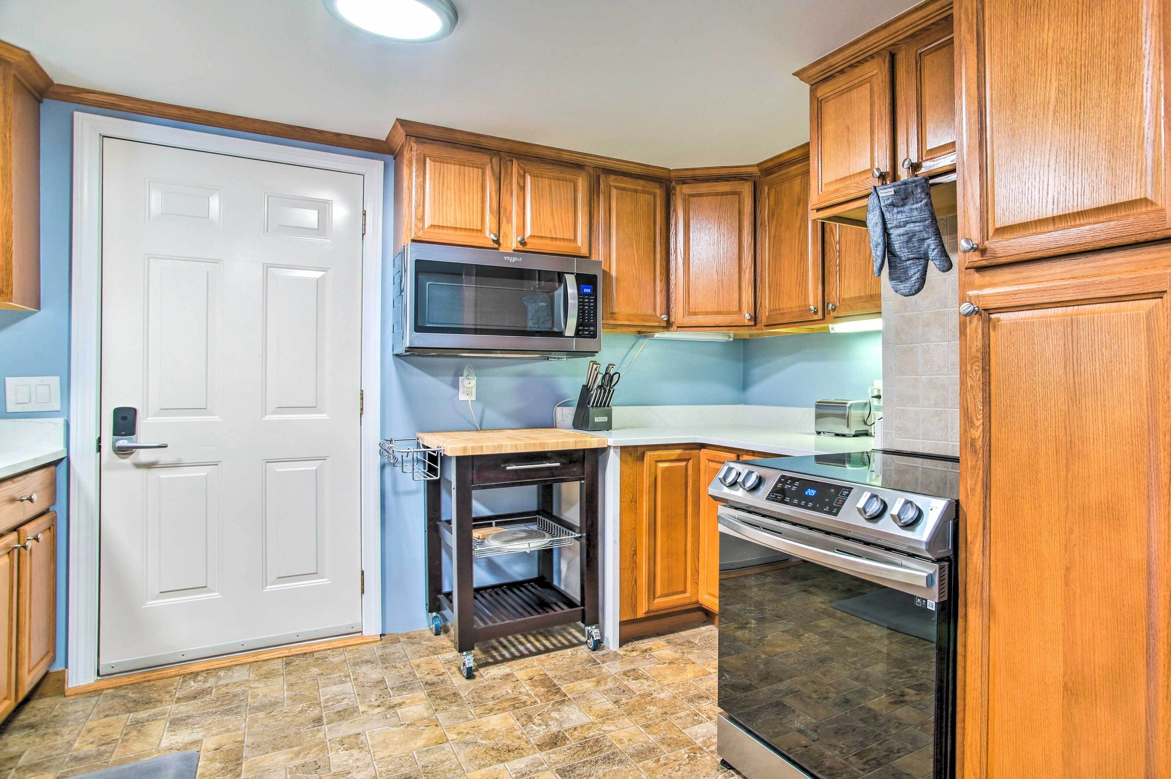 A compact kitchen with wooden cabinets, a microwave, an oven, and a small countertop.