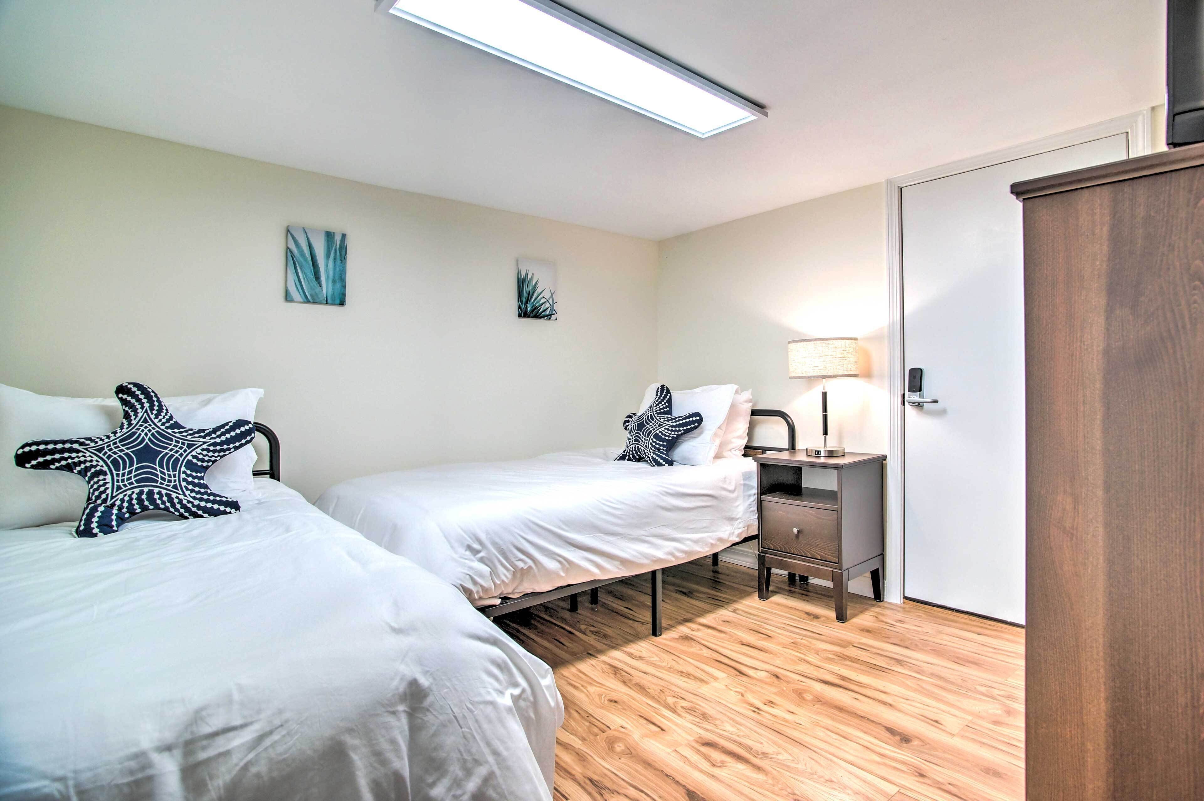 A bedroom with two beds, a desk, a lamp, and a wardrobe.