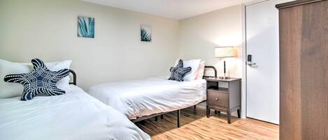A bedroom with two beds, a desk, a lamp, and a wardrobe.