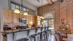 Une cuisine moderne avec des meubles en bois, des appareils en acier inoxydable et un coin bar avec des tabourets.