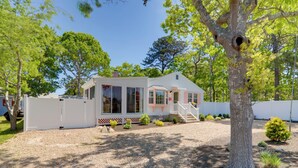 A single-story house with a porch, a chimney, and a small deck. - Charming West Yarmouth Home ~ 2 Mi to Beach! (West Yarmouth)