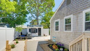 A residential property with a wooden deck, a small garden with various plants, and a white fence. - Charming West Yarmouth Home ~ 2 Mi to Beach! (West Yarmouth)