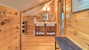Un baño de cabaña de madera con dos lavamanos, un espejo y un banco.